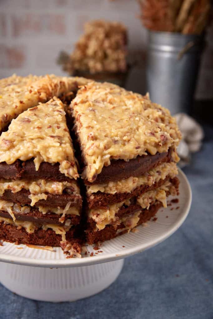 German chocolate cake layers split in half on a cutting board with a serrated knife for assembling four layers.