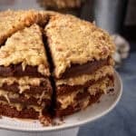 Close-up of sliced German chocolate cake on a cake stand, showing thick layers of coconut pecan frosting.