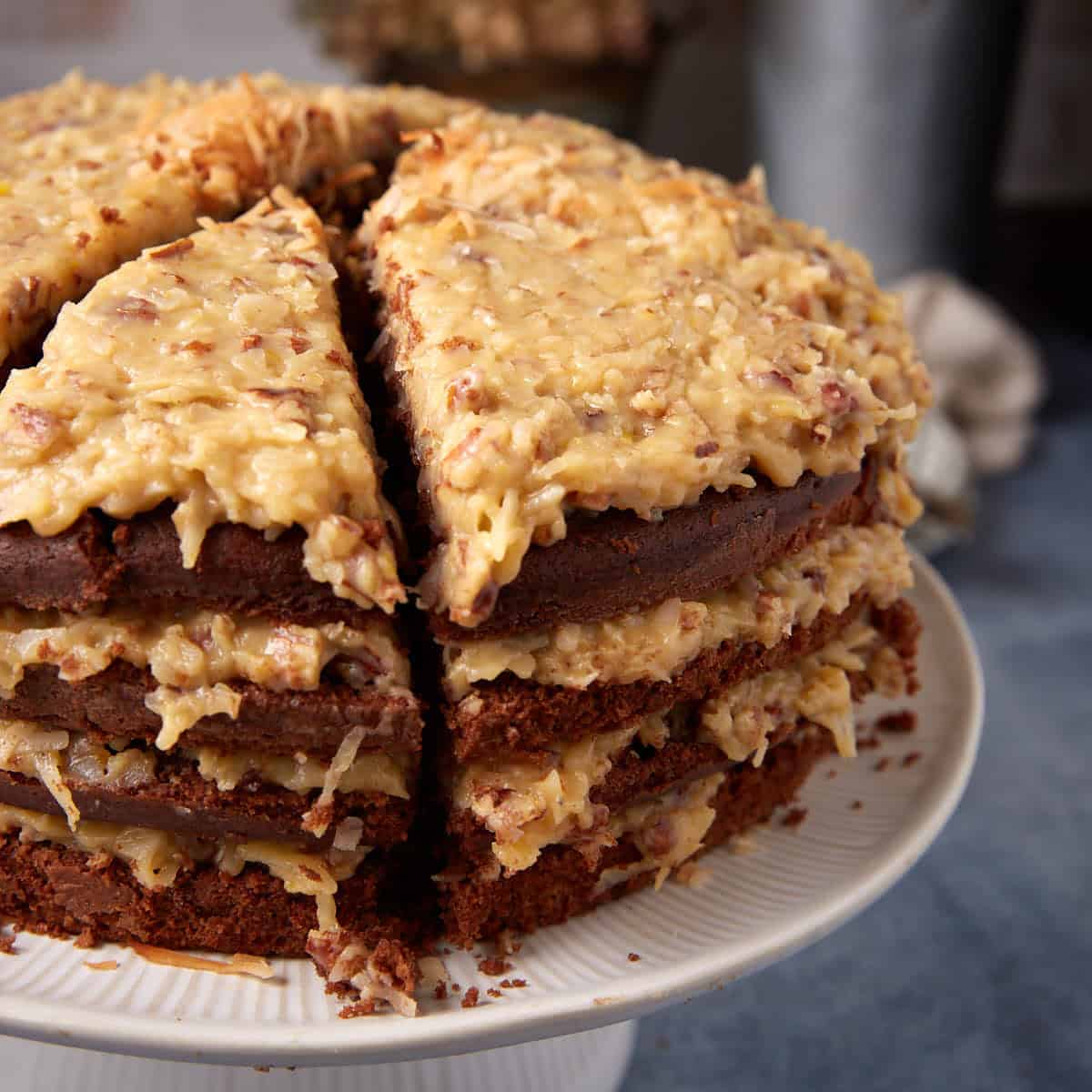 Close-up of sliced German chocolate cake on a cake stand, showing thick layers of coconut pecan frosting.
