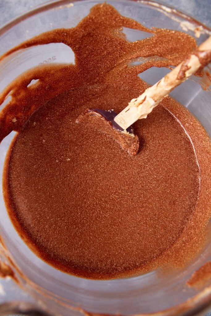 Chocolate mixture in a bowl after sugar has been added, ready to be whisked smooth.