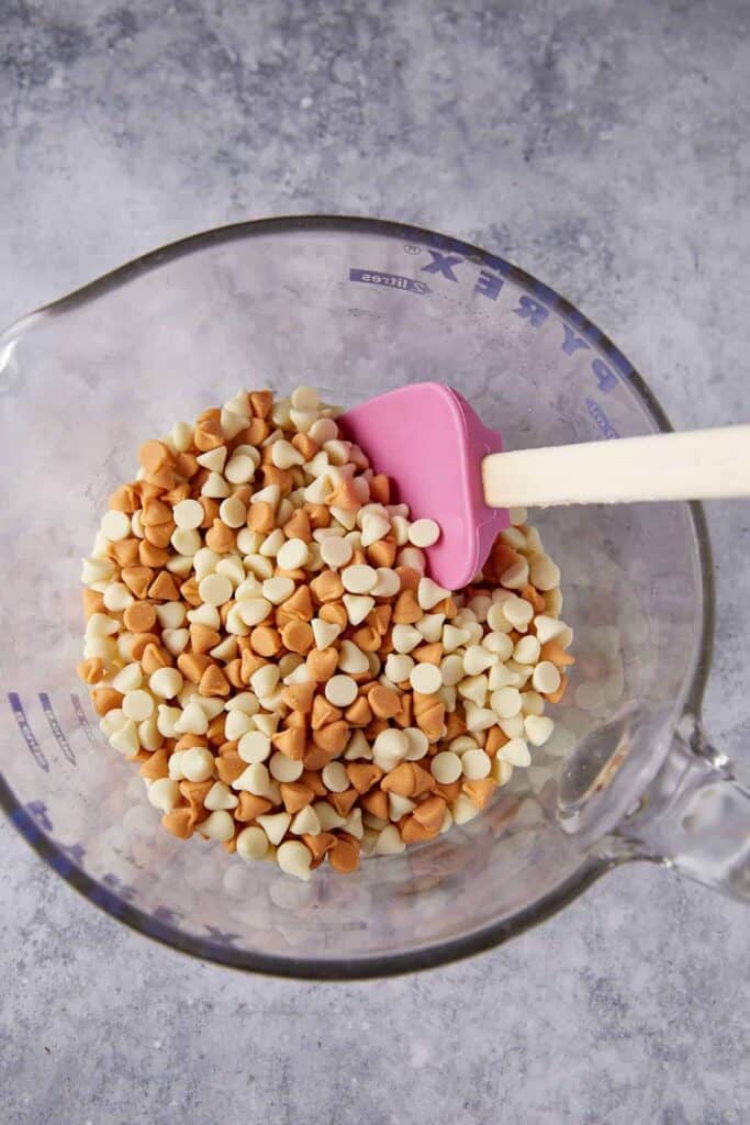 White chocolate and butterscotch chips in a glass measuring bowl before melting for haystack cookies.