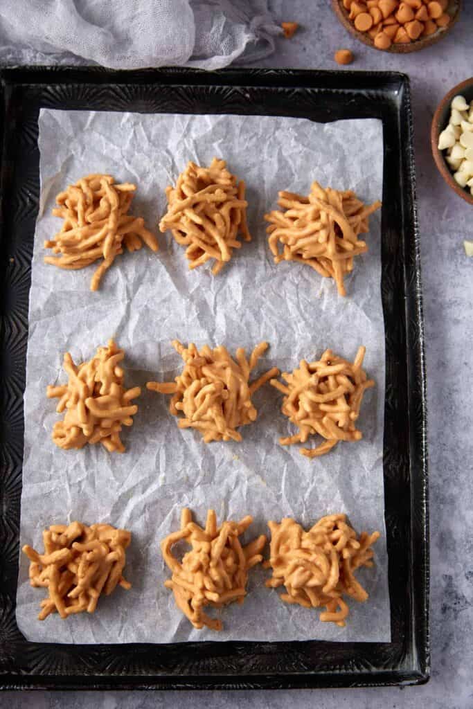 No-bake haystack cookies set on a parchment-lined black tray.