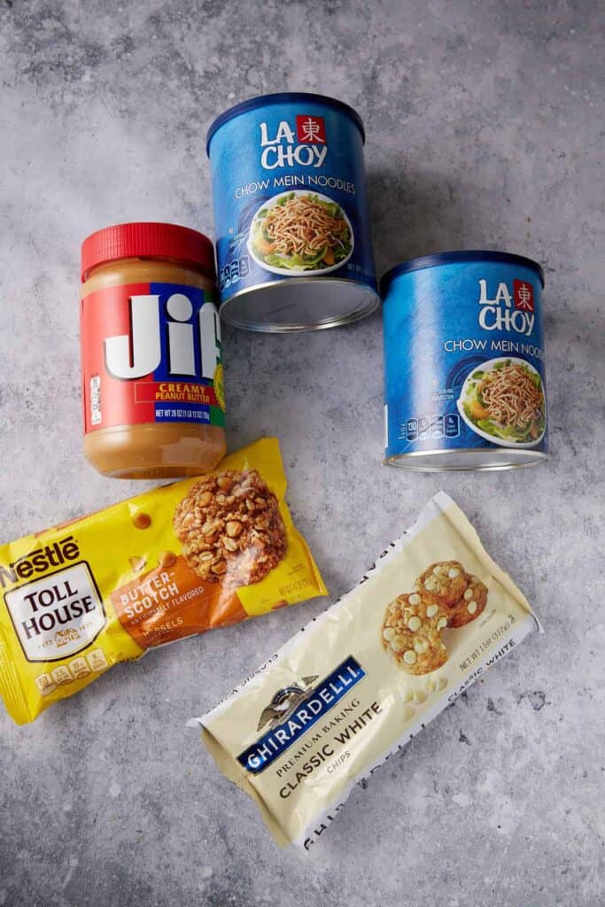 Four ingredient haystack cookie ingredients including peanut butter, chow mein noodles, butterscotch chips, and white chocolate chips.