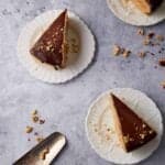 Overhead view of two slices of peanut butter pie with chocolate topping on white plates with a pie server nearby.