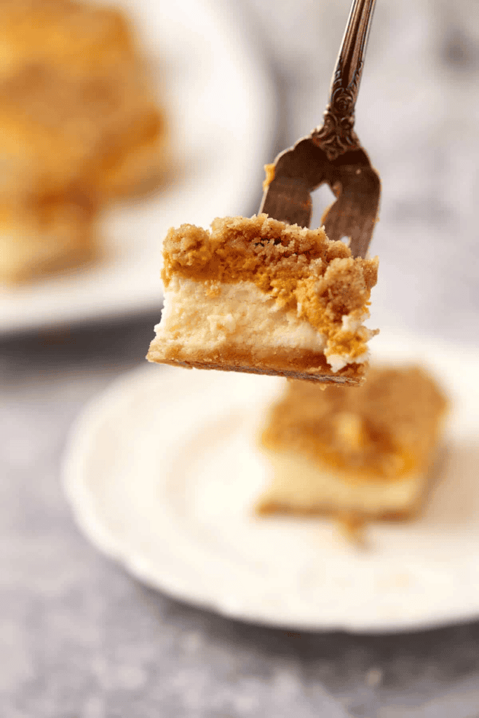 A bite on a fork of pumpkin cheesecake bars.