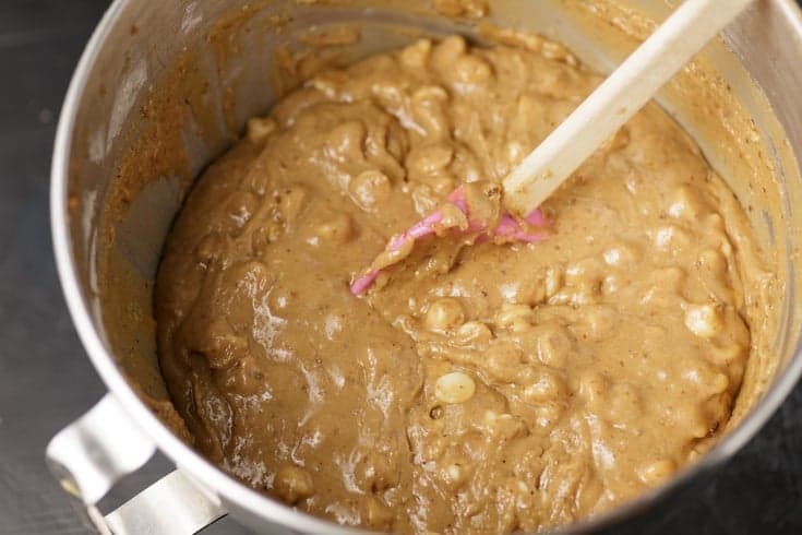 Thick blondie batter with white chocolate chips mixed in a stand mixer bowl.