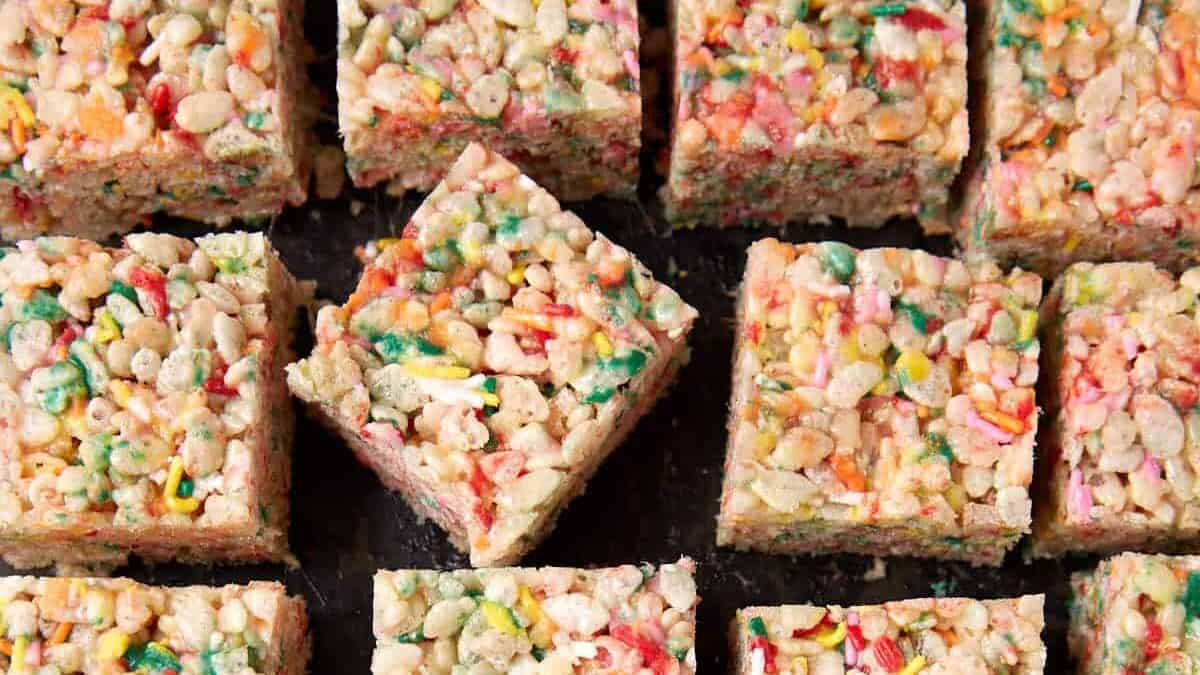 Rice Krispie treats with sprinkles on a dark plate, showing the soft center and colorful marshmallow