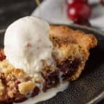 Close-up of cherry crumb pie with melting vanilla ice cream.