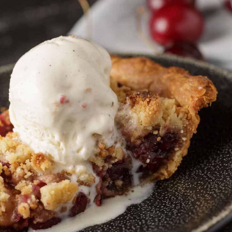 Close-up of cherry crumb pie with melting vanilla ice cream.