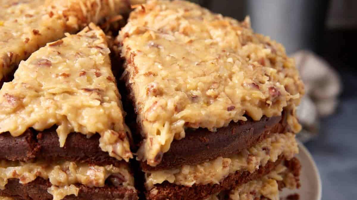 German chocolate cake layers split in half on a cutting board with a serrated knife for assembling 