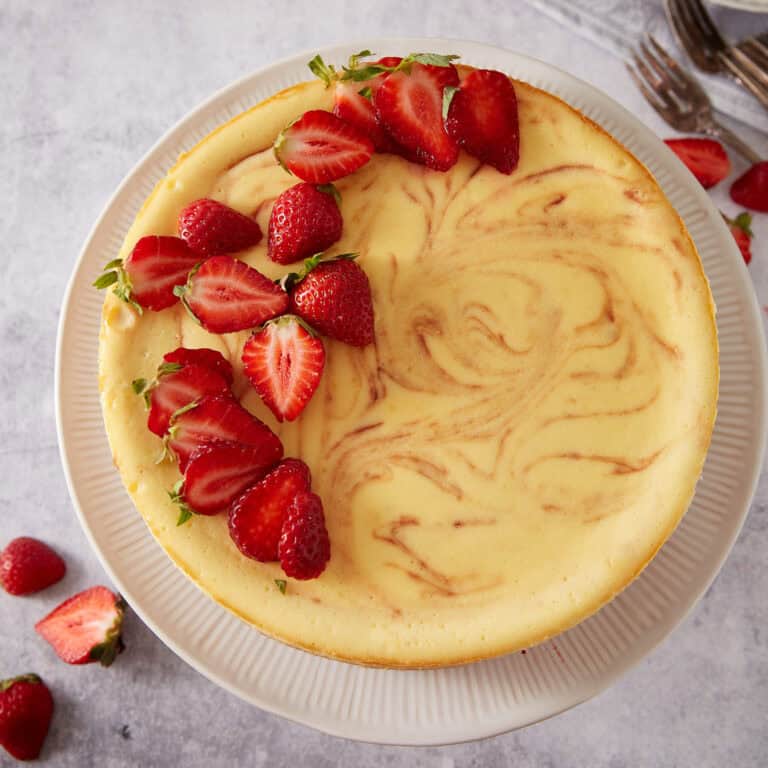 Strawberry swirl cheesecake topped with fresh sliced strawberries.