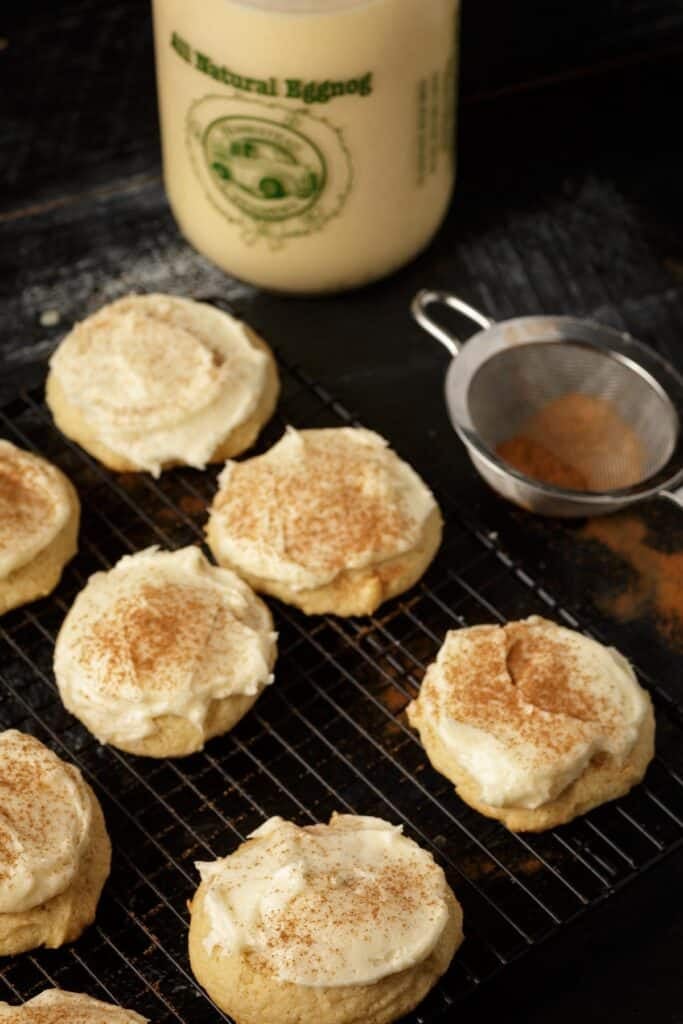 A rack of soft eggnog cookies next to a bottle of eggnog.