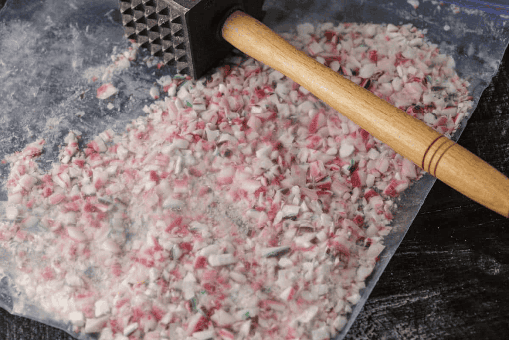 A meat tenderizer mallet crushing peppermint candies inside a plastic bag.