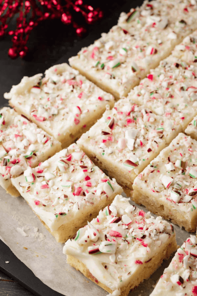 Square sugar cookie bars topped with white frosting and crushed peppermint candy.